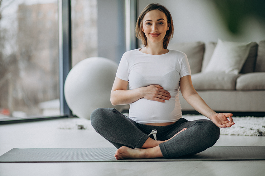 Pregnant woman practicing Lamaze breathing techniques in a seated position, preparing for childbirth.