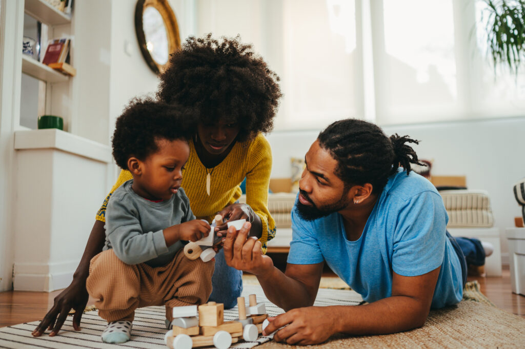  African-American family engaging in play to foster emotional intelligence in their young child.