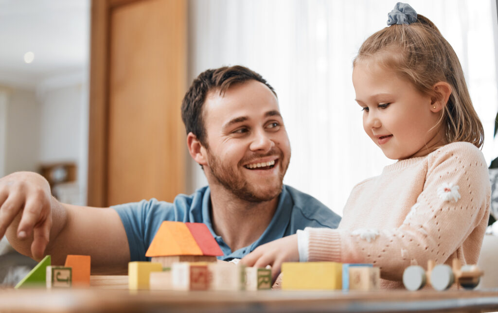 Father and daughter building emotional intelligence through interactive play with building blocks.